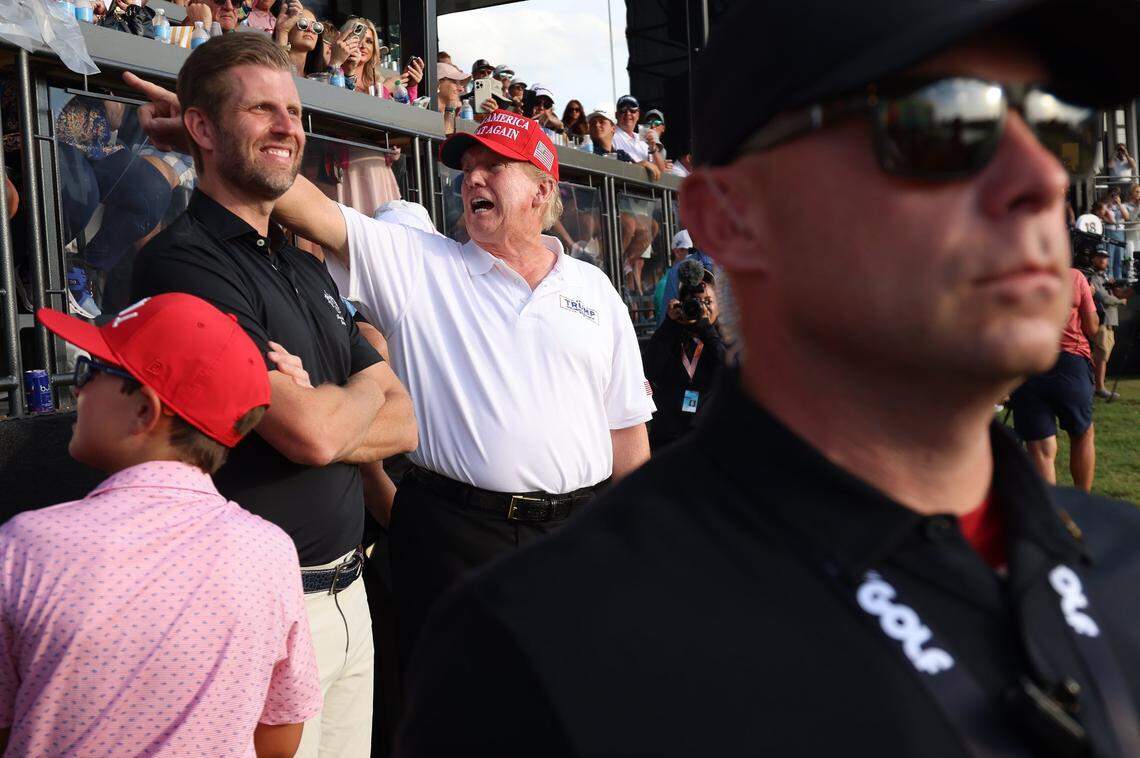 President Donald Trump points to supporters next to his son Eric Trump, left, at the LIV Golf Miami tournament on the 18th Hole at Trump National Doral on April 7, 2024.