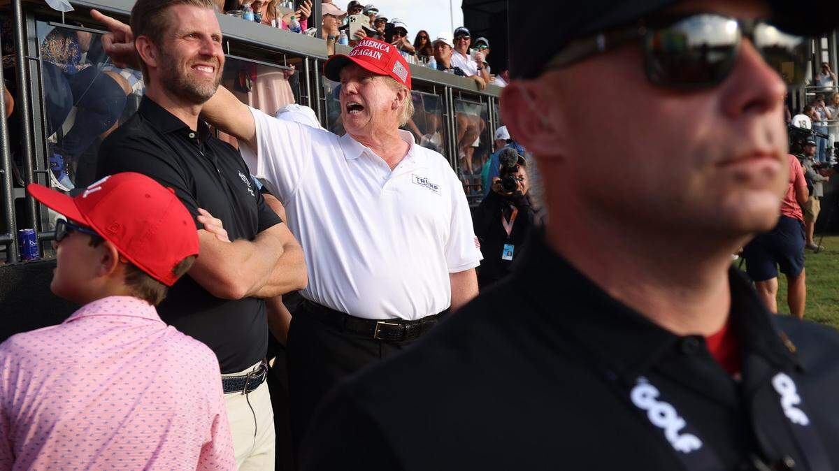Donald Trump points to supporters next to his son Eric Trump, left, at the LIV Golf Miami tournament on the 18th Hole at Trump National Doral on April 7, 2024.