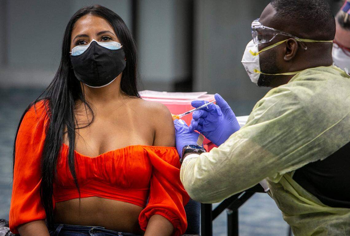 Miami, Florida, May 9 2021 - Sigrey Gonzalez Flores (left) from Costa Rica, gets her Pfizer vaccine at the pop up vaccination site in Concourse D in the 4th floor auditorium at Miami International Airport.