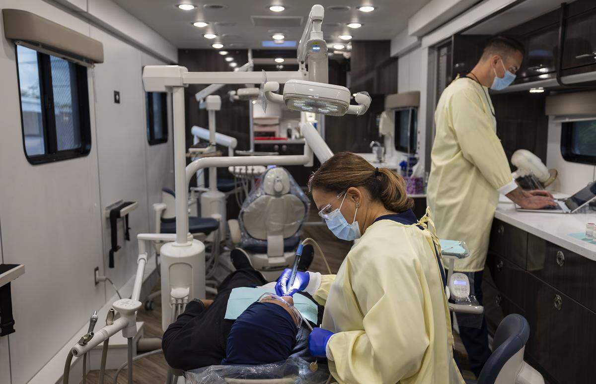 Damaris Ortiz, a dental hygienist with Caring for Miami, performs a dental cleaning for Sahar Mansour inside the Mobile Dental Clinic in Opa-locka. UHI CommunityCare Clinic and Caring for Miami are providing free dental care for uninsured and underserved residents every Thursday. 