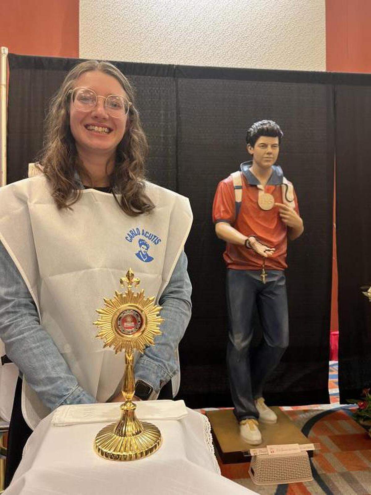 Volunteer Rachel Schuett stands near a relic of soon-to-be saint Carlo Acutis during a conference organized by the Servants of the Pierced Hearts of Jesus and Mary, which drew 4,000 people to Miami in 2022.