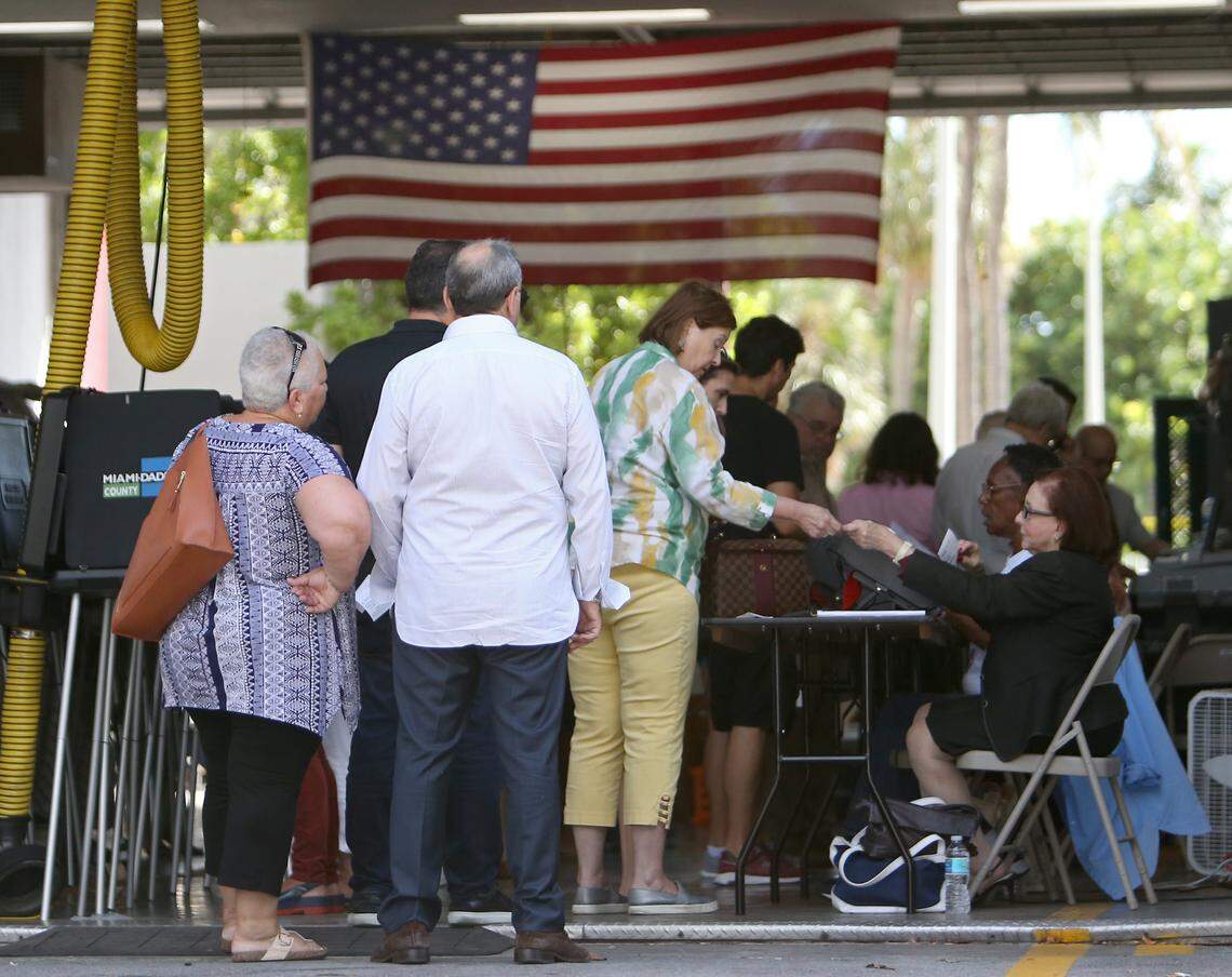Poll workers help people check in as voters cast their votes at Miami Beach Fire Station #3 on Tuesday, Nov. 6, 2018.