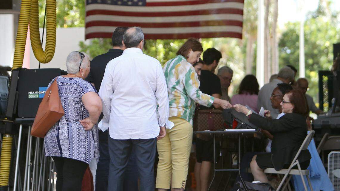 Poll workers help people check in as voters cast their votes at Miami Beach Fire Station #3 on Tuesday, Nov. 6, 2018.