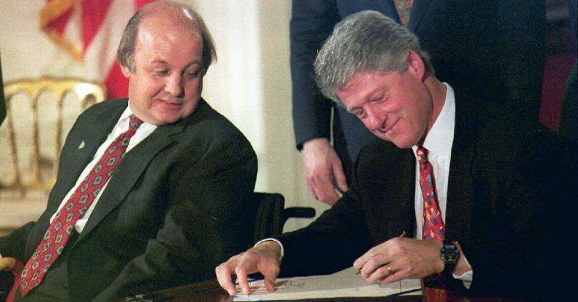 In 1993, 12 years after he was wounded by John Hinckley Jr. during an assassination attempt on President Ronald Reagan, James Brady watches President Bill Clinton sign into law the Brady Bill mandating federal background checks for gun purchasers.