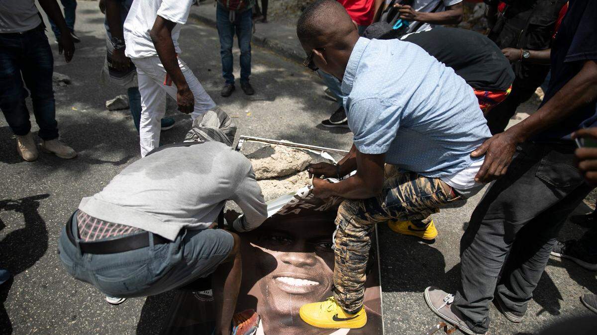 Demonstrators destroy a street sign they took down of slain President Jovenel Moise during a demonstration against increasing violence in Port-au-Prince, Haiti, Tuesday, March 29, 2022. Violence, some of it gang related, has flared again this week.