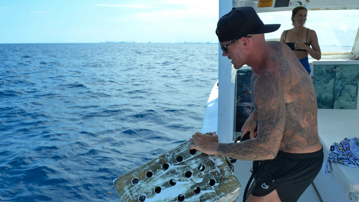 Johnny Matthews, one of Florida Shark Diving’s charter boat captains, throws a white, rusted crate full of chum into the water off the coast of Jupiter, Florida, to attract sharks on June 12, 2026.