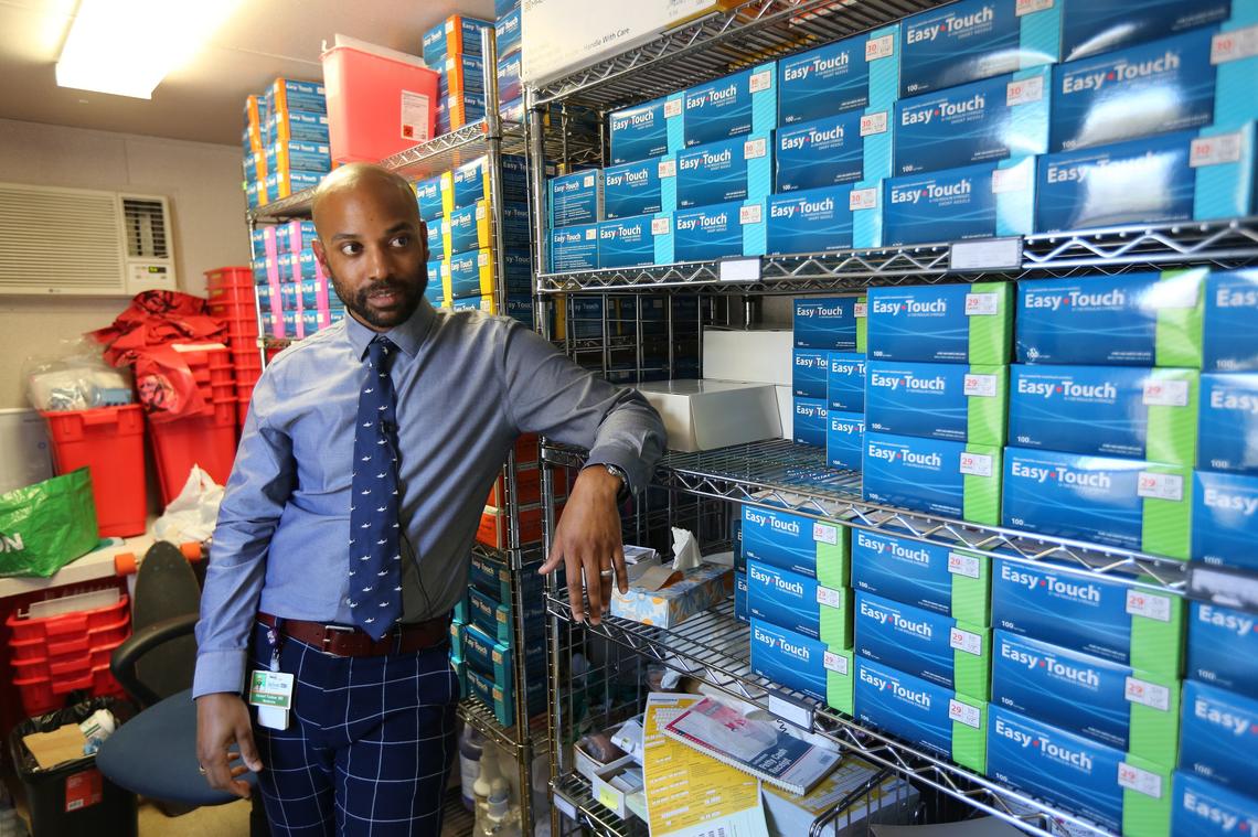 Dr. Hansel Tookes, who fought for and started Miami’s IDEA Needle Exchange, stands by stacks of syringes in the program’s supply room.
