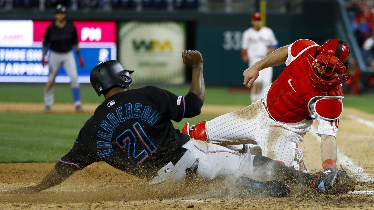 Philadelphia Phillies catcher J.T. Realmuto, right, tags out Miami Marlins’ Curtis Granderson at home after Grandson tried to score on a single by Miguel Rojas during the sixth inning of a baseball game, Saturday, April 27, 2019, in Philadelphia. (AP Photo/Matt Slocum)