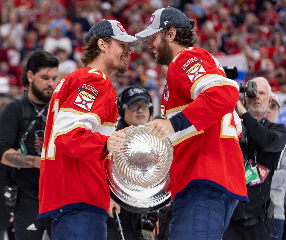 Florida Panthers center Carter Verhaeghe (23) hands center Nick Cousins (21) the Stanley Cup after defeating the Edmonton Oilers in Game 7 of the Stanley Cup Final at Amerant Bank Arena on Monday, June 24, 2024, in Sunrise, Fla.