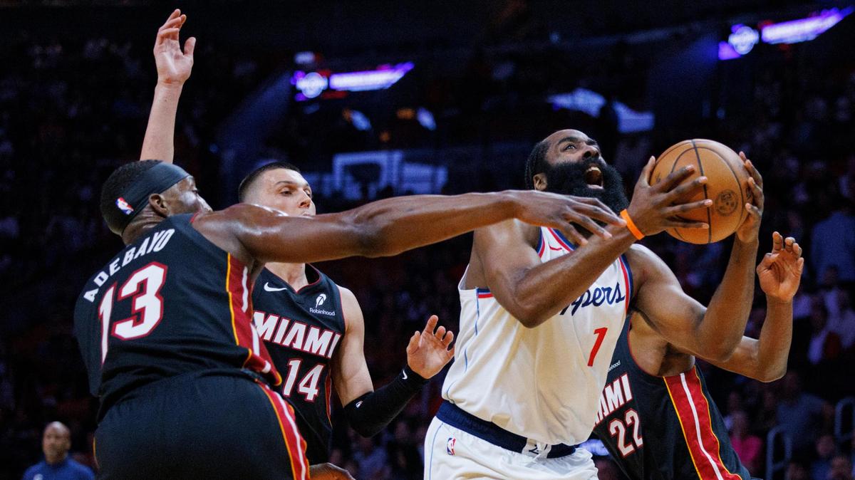 LA Clippers guard James Harden (1) attempts to shoot while guarded by Miami Heat center Bam Adebayo (13) and forward Andrew Wiggins (22) during the first half of a game on March 12, 2025, at Kaseya Center in Miami.