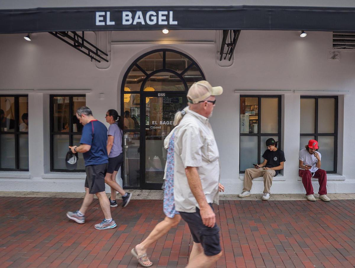 Employees Lucas Diaz, second from the right, and Danny Padron, right, take a quick break outside the new El Bagel location in Coconut Grove.
