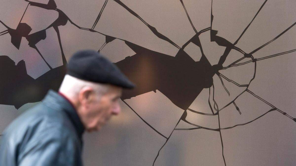 In Berlin, a man walks past a shop window decorated with a sticker simulating broken glass ahead of a commemoration of the 1938 Kristallnacht pogroms targeting Jews.