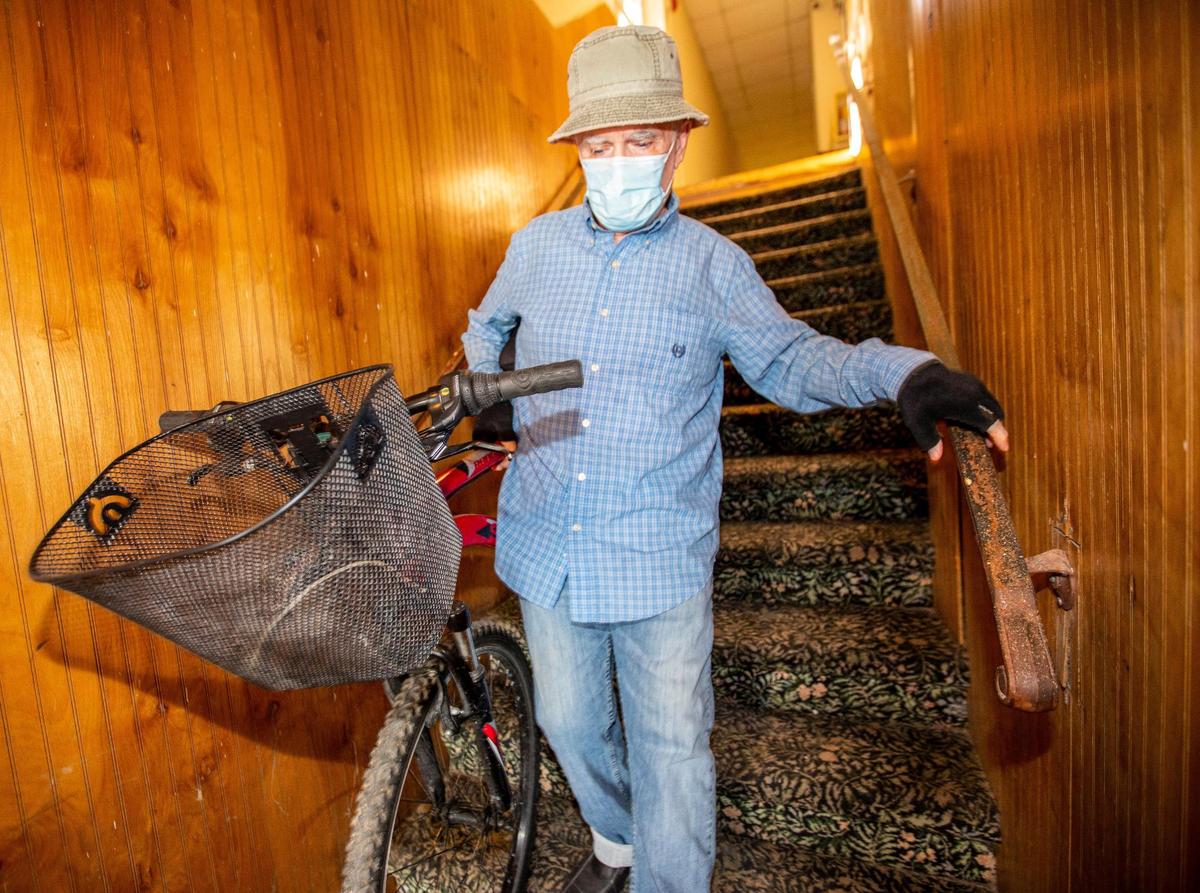 Tenant John Crawford, who has lived at 532 N. Miami Ave. for 10 years and is currently unemployed, walks his bike down the stairs at the Arena Hotel in Miami, on Dec. 29, 2020. ‘This is an affordable place to live,’ says Crawford, who rents a room from landlord Ron Bazak, who is in the midst of a fight and apparent stalemate with the City of Miami over code violations.
