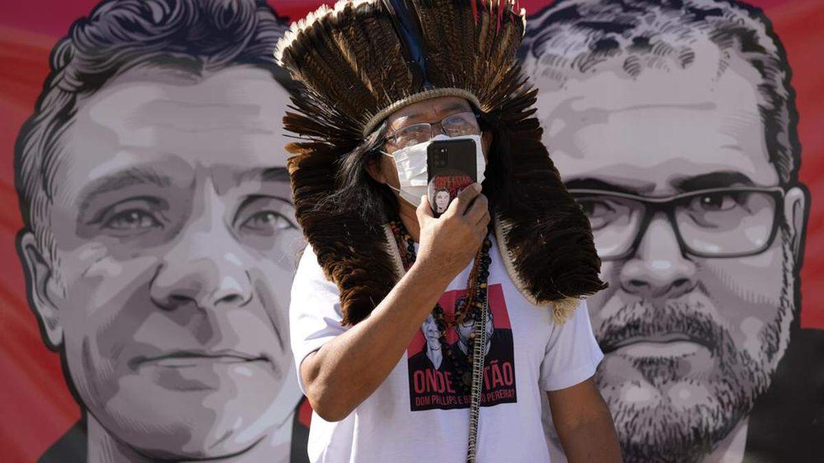 Indigenous leader Kamuu Wapichana stands in front of a banner with images of freelance British journalist Dom Phillips, left, and Brazilian Indigenous expert Bruno Pereira.