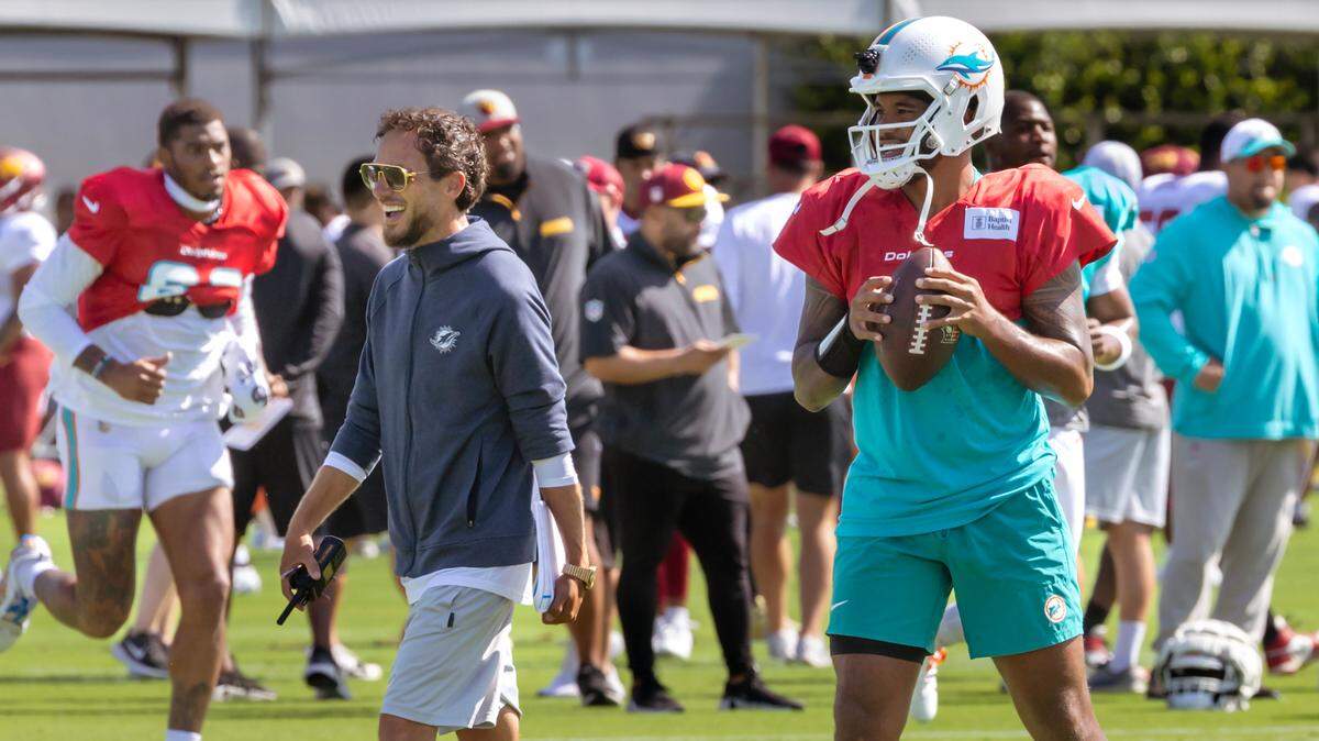 Miami Dolphins head coach Mike McDaniel talks with Dolphins quarterback Tua Tagovailoa (1) sets up to pass during team practice at the Baptist Health Training Complex on Thursday, Aug. 15, 2024, in Miami Gardens, Fla.
