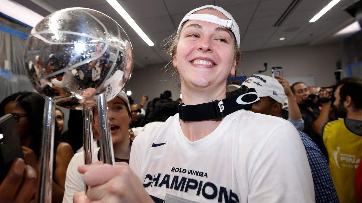Washington Mystics center Emma Meesseman holds the trophy in the locker room after Game 5 of basketball’s WNBA Finals against the Connecticut Sun, Thursday, Oct. 10, 2019 in Washington.