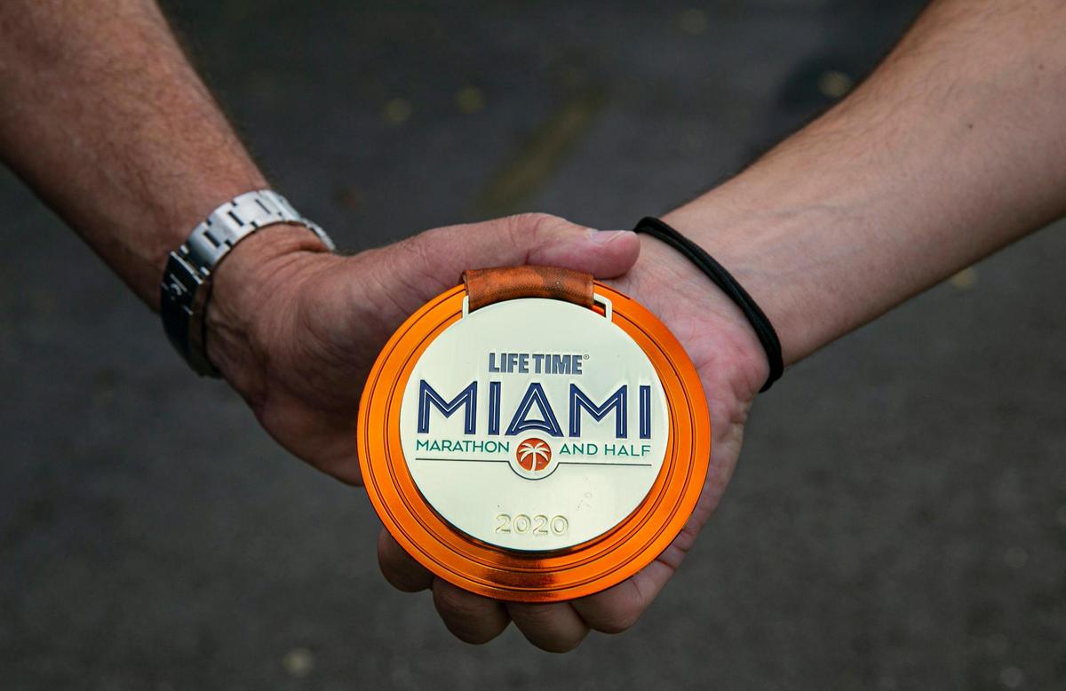 Martin Langesfeld, 24, and his father, Pablo Langesfeld, 56, hold a 2020 Miami Marathon medal belonging to Nicole Langesfeld at the Turnpike Trail in Doral on Wednesday, Jan. 26, 2022.