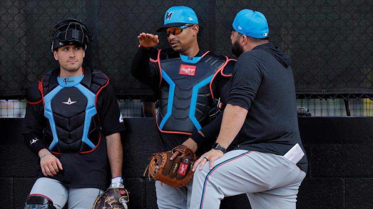 Marlins catchers Nick Fortes (left) and Christian Bethancourt (center) talk with coach Rod Barajas during Miami Marlins pitchers and catchers spring training workout at Roger Dean Chevrolet Stadium in Jupiter, Florida on Thursday, February 15, 2024.