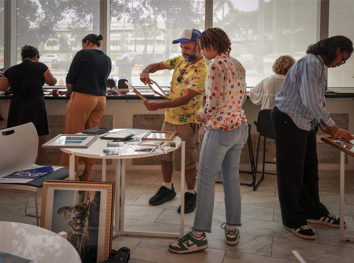Artistic director Christopher Mitchell, center, helps Shayna Lowertow, 17, as others assist in framing of the artwork for installation as four high school students installed photos inside the First Church Miami coffee shop for the exhibition Sparrow, featuring the photography of local photographers navigating homelessness under the artistic direction of Miami-based artist Christopher Mitchell on Sunday, November 30, 2025.