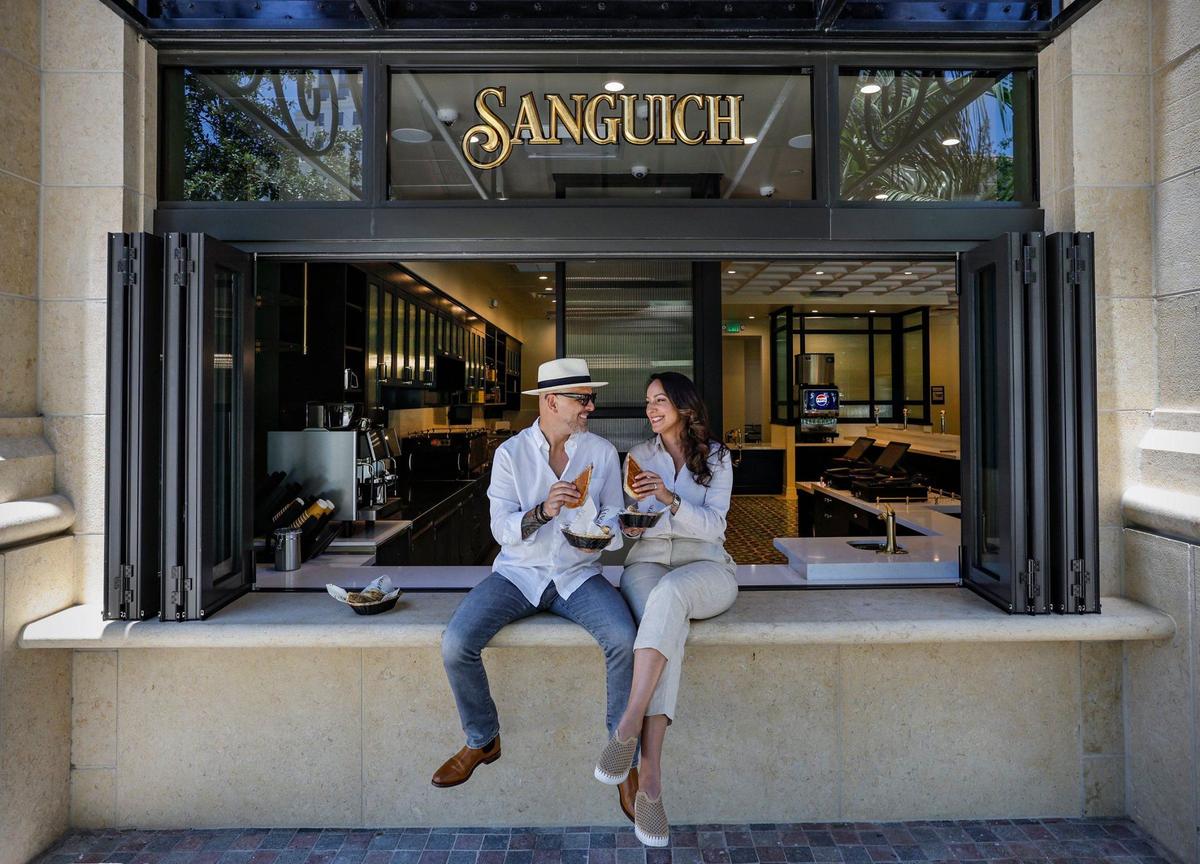 Husband-and-wife team Daniel Figueredo and Rosa Romero, owners of Sanguich, sit on the ledge of the ventanita of their new restaurant in Coral Gables.