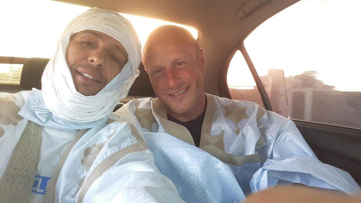Former captive Mohamedou Ould Slahi, wearing an ACLU T-shirt under his traditional robe, making a selfie with his former  Guantánamo guard, Steve Wood, who he gave a matching robe during a three-day Ramadan reunion in Mauritania in May 2018.