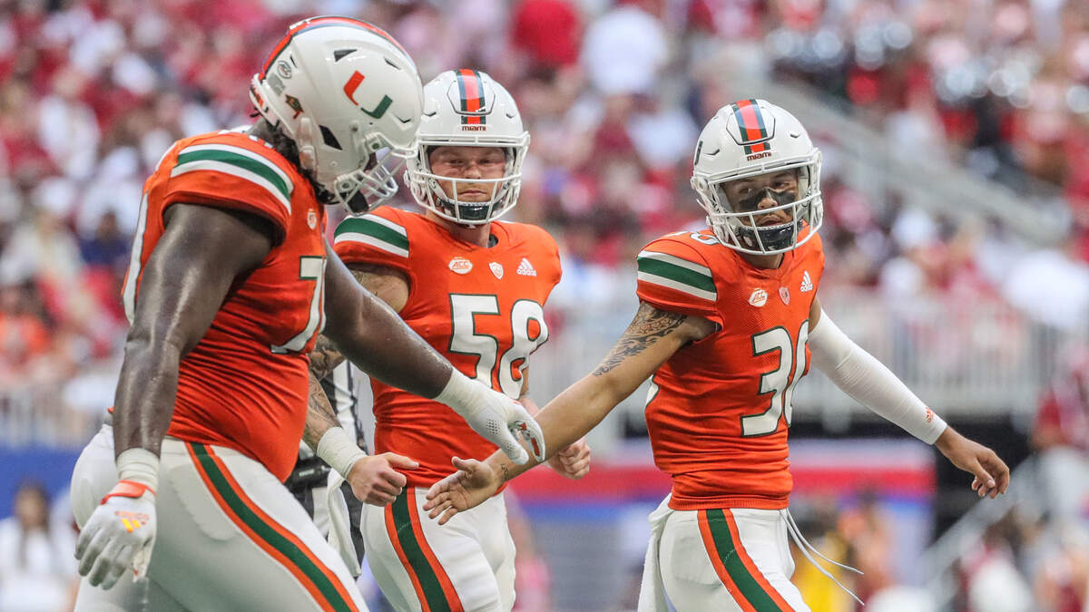 El kicker de los Miami Hurricanes, Andrés Borregales (30), celebra con sus compañeros de equipo, el offensive lineman Justice Oluwaseun (70) y el long snapper Clay James (58) después de que Borregales pateara un gol de campo en el tercer cuarto en el Mercedes-Benz Stadium en Atlanta, el sábado 4 de septiembre de 2021.