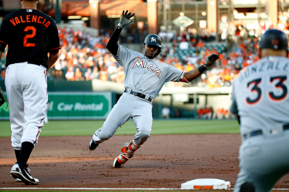 Miami Marlins' Lewis Brinson triples in front of Baltimore Orioles third baseman Danny Valencia (2) and Marlins third base coach Fredi Gonzalez in the second inning of a baseball game, Friday, June 15, 2018, in Baltimore. (AP Photo/Patrick Semansky)