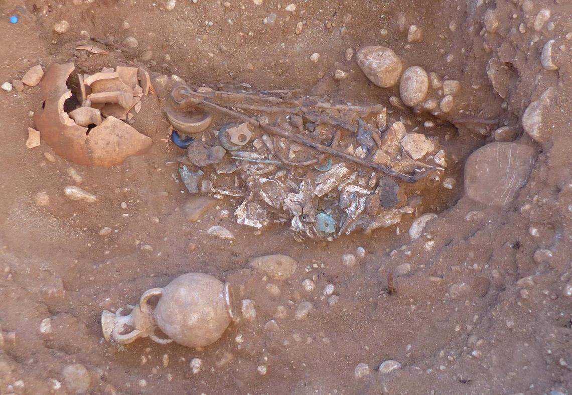 An adult buried in a wooden box with oil lamps, tongs, spoons and bracelets.