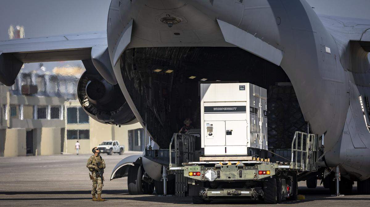 Port-au-Prince, Haiti, May 15, 2024 - A United States serviceman, left, stands guard as supplies are offloaded from a US Air Force C-17 cargo plane on the tarmac at Toussaint Louverture International Airport in Port-au-Prince, Haiti. 
The plane was carrying supplies for the camp being built for Kenyan police officers who will lead a Multinational Security Support mission into Haiti.



