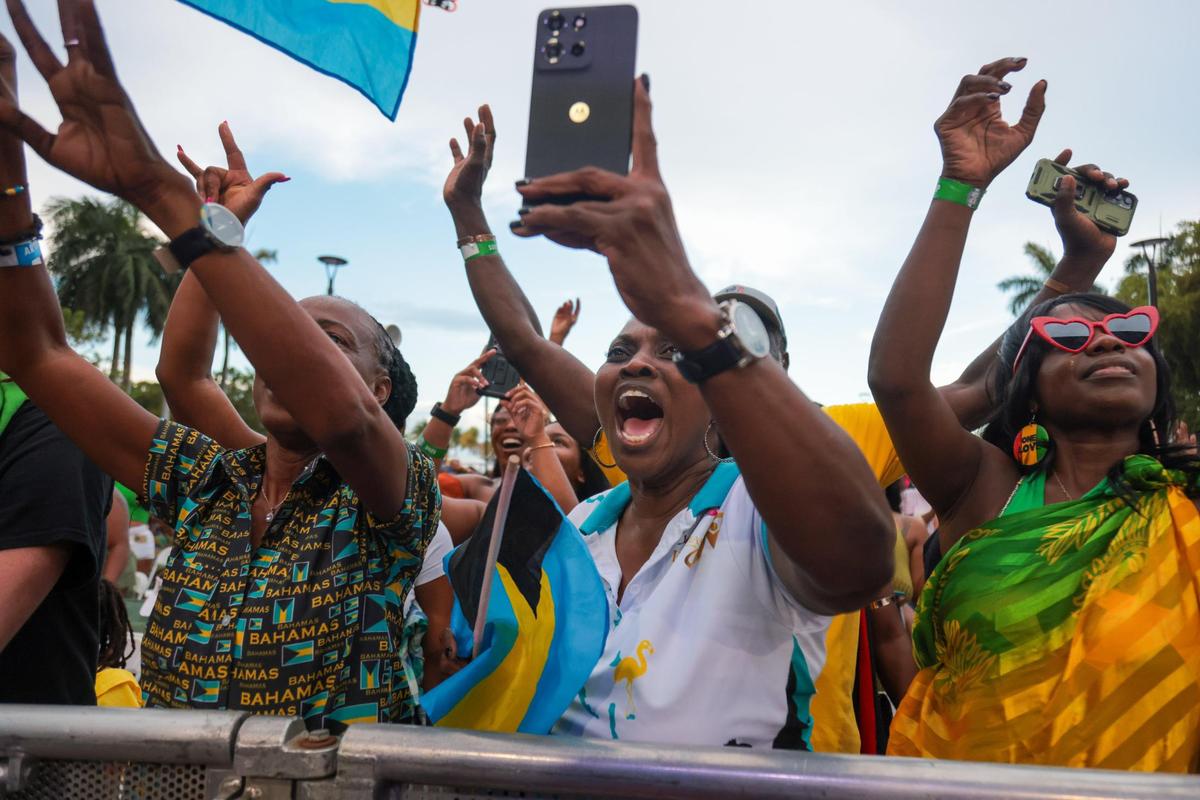A woman, holding a Bahamian flag, reacts to the music during the 19th annual Best of the Best International Music Festival at Bayfront Park in downtown Miami, Sunday, May 25, 2025.