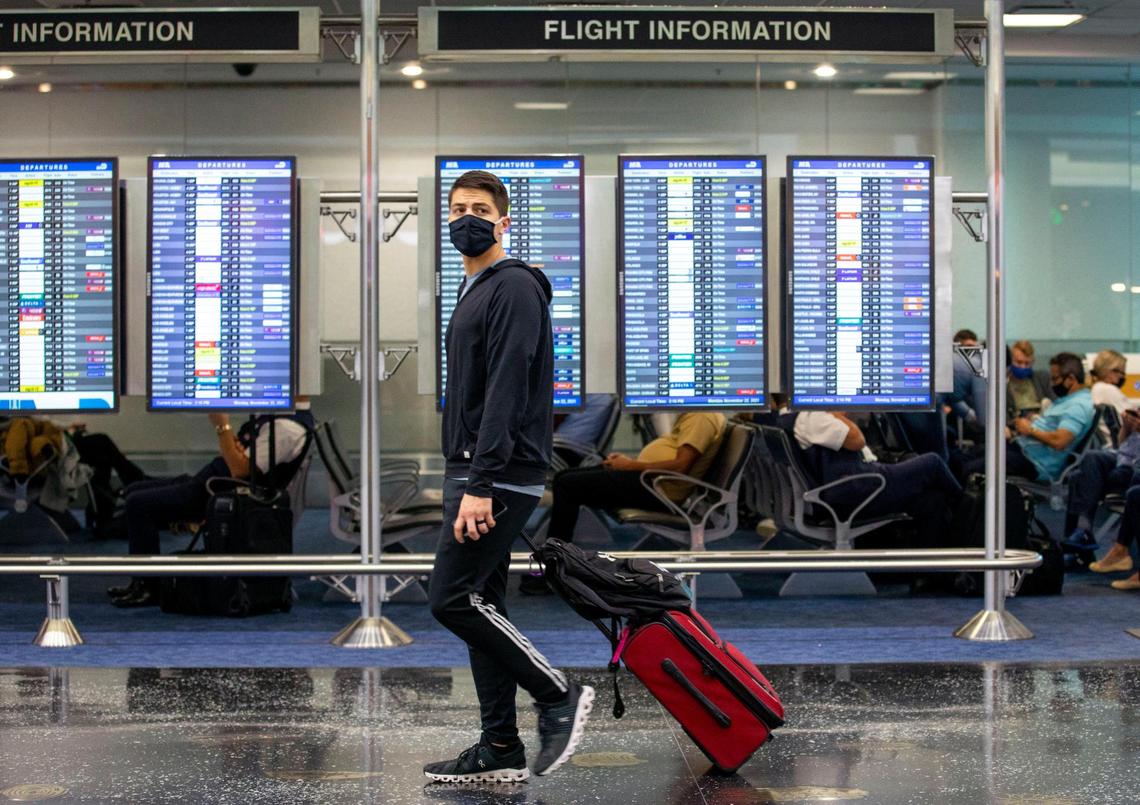A traveler pulls along his luggage while walking through a concourse at Miami International Airport in Miami, Florida, on Tuesday, November 23, 2021.