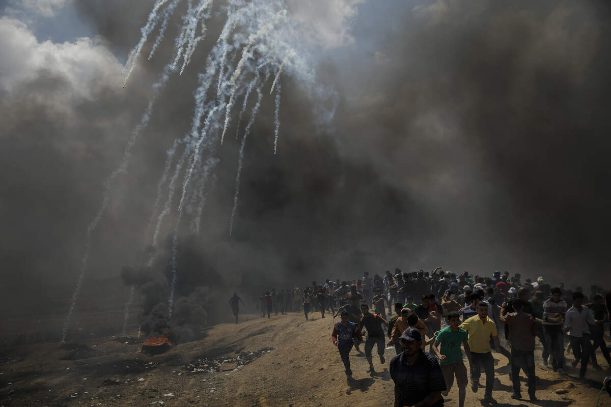 Protesters run away from tear gas dispersed by Israeli forces as they inch closer to the border fence separating Israel and Gaza in a camp east of Gaza City, Gaza on Monday, May 14, 2018.