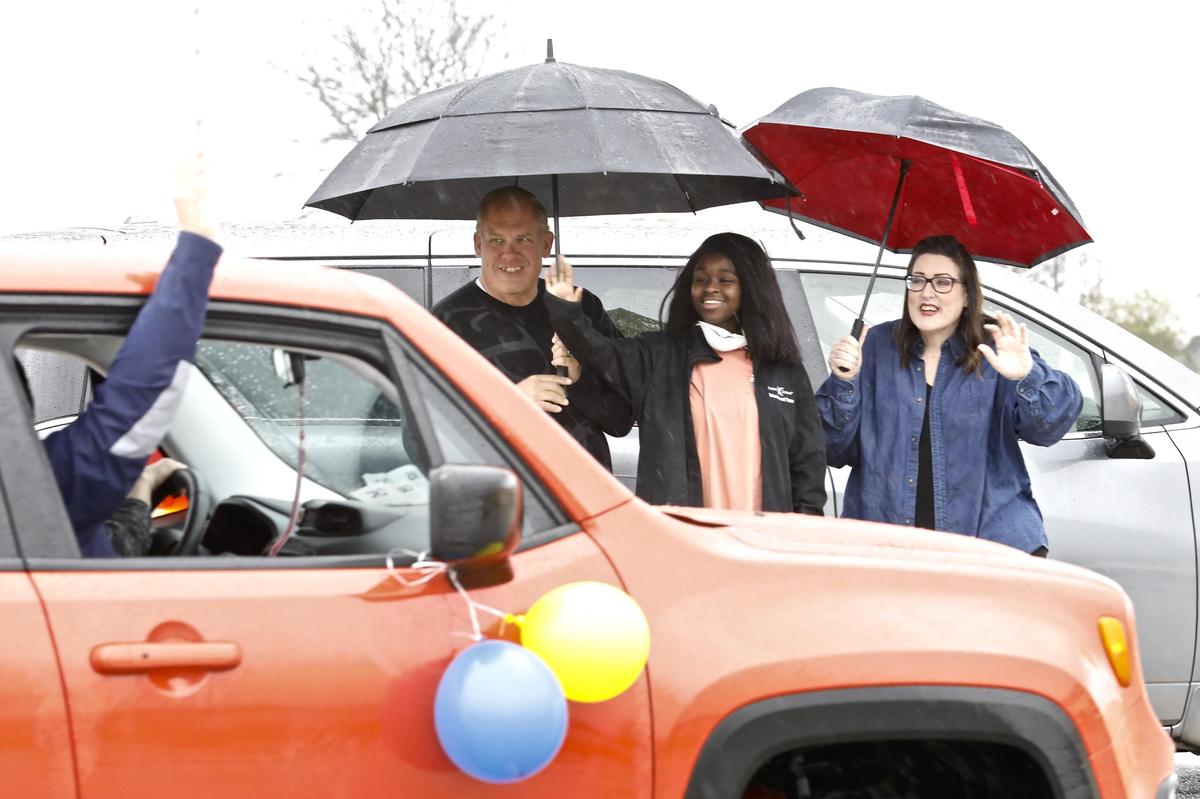 Julia Whitcomb, center, and her parents Jim and Lisa Whitcomb, all of Poplar Grove, wave as friends parade by in vehicles at the former Shopko parking lot in Belvidere Sunday, May 10, 2020, welcoming Julia back from a cruise ship quarantine.