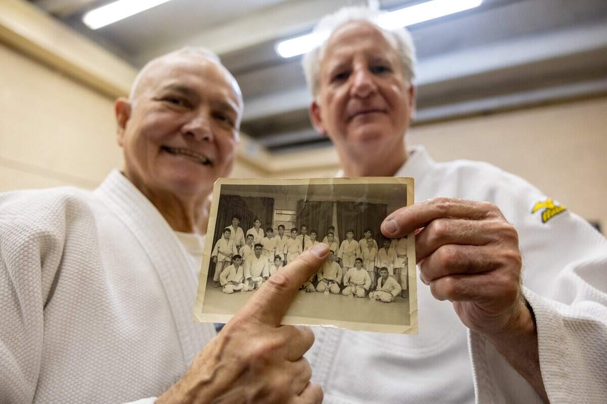 Alberto Fernandez, president of Baragua Judo Kai, left, and Peter Iglesias, a Baragua Judo Kai instructor, right, point to themselves in an old Judo class photo at Baragua Judo Kai in Miami, Fla., on Wednesday, June 3, 2026.