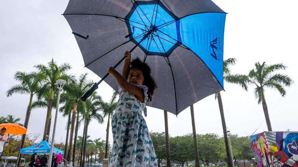Young Miami Marlins fan Melanie Guerra, 3, twirls an umbrella outside the ball park before the first inning of an MLB game against the New York Mets at LoanDepot Park in Miami, Florida, on Thursday, March 30, 2023.