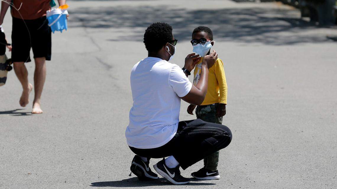 A man adjusts a child’s mask before heading to the sand at Orchard Beach in the Bronx borough of New York in 2020. On Monday, April 25, the Food and Drug Administration ​approved Veklury as the first COVID-19 treatment for children younger than 12.
