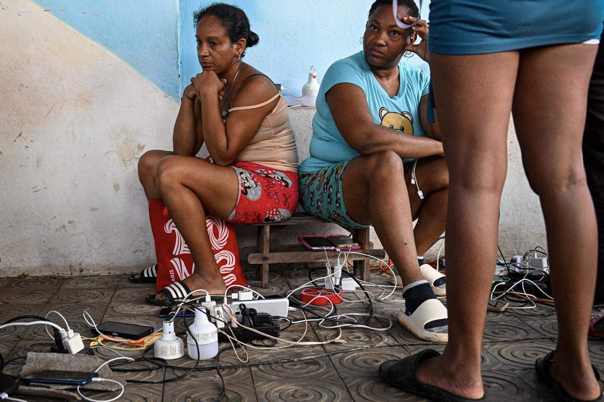 Residents of the town of El Cobre, in the province of Santiago de Cuba, charge their mobile phones after the passage of Hurricane Melissa, on October 29, 2025. 