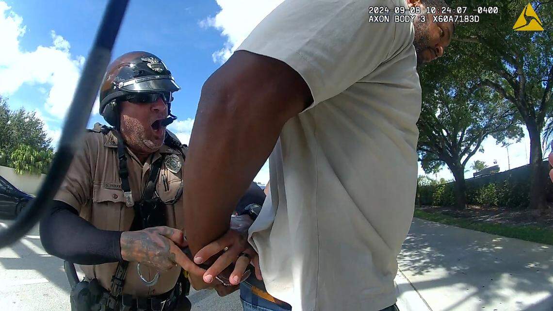 Miami-Dade Police officer Danny Torres handcuffs Miami Dolphins defensive tackle Calais Campbell who had stopped to help his teammate Tyreek Hill. Hill, a star receiver for the Dolphins, had been detained by Miami-Dade Police for speeding Sunday, Sept. 8, 2024, near Hard Rock Stadium.
