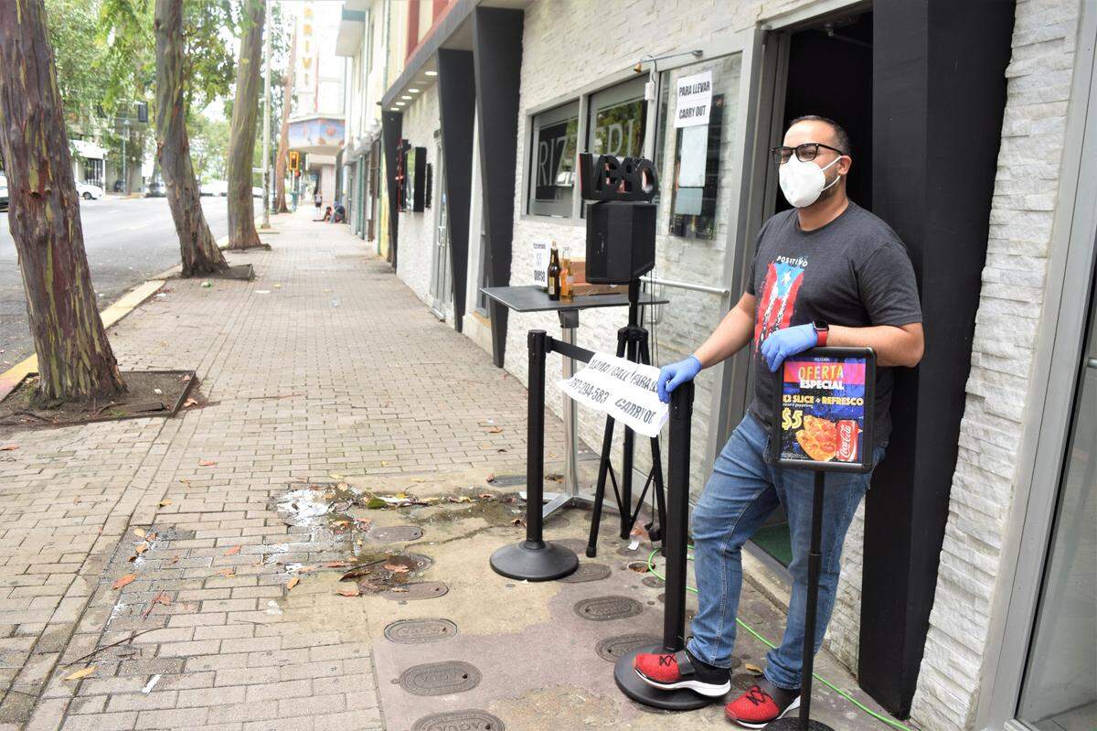 Jose Matos stands outside his pizzeria, Rizzeria, in San Juan, Puerto Rico. People secluded at home during the coronavirus lockdown are ordering takeout.