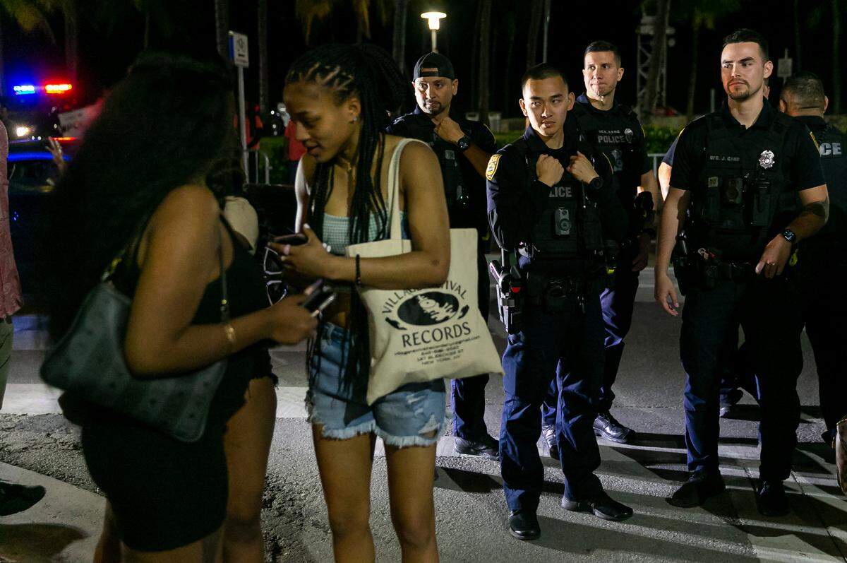 A group of police officers gather on Ocean Drive and 8th Street in Miami Beach, Florida on Friday, March 25, 2022. City officials imposed a midnight curfew and forced stores to stop selling alcohol after 6 p.m. The restrictions were set in place after two shootings in Miami Beach the weekend before caused city officials to announce a “state of emergency.”