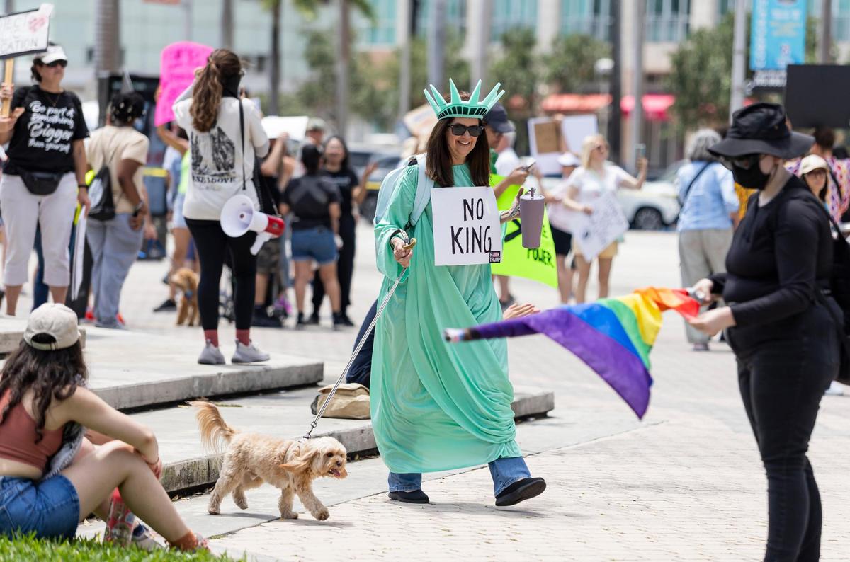 An activist dressed up as the Statue of Liberty attends a National Day of Action protest against President Donald Trump and his administration at the Torch of Friendship on Saturday, April 19, 2025, in downtown Miami, Fla.