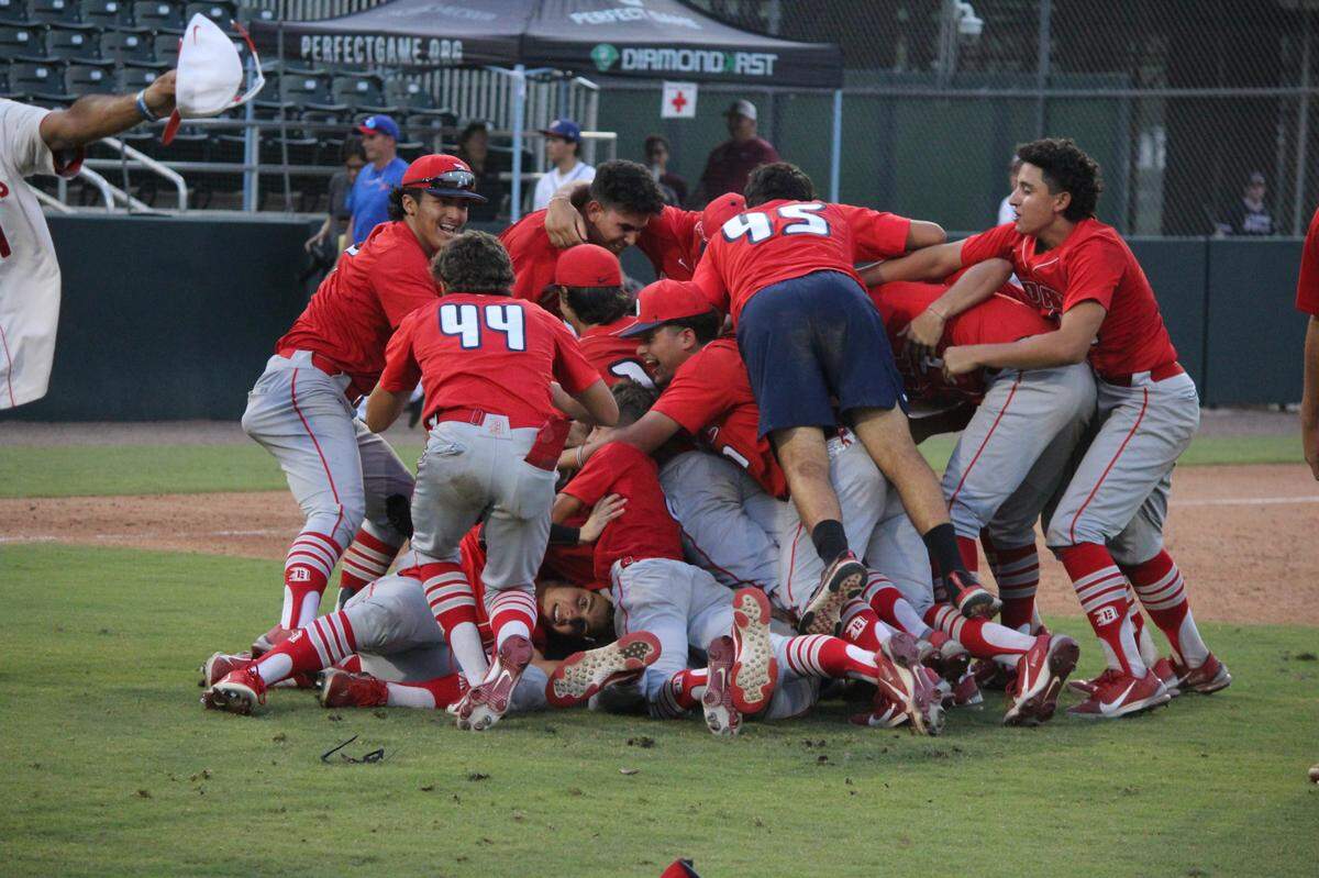 Doral Academy baseball players pile on each other after winning their first state championship on Saturday night at Hammond Stadium in Fort Myers