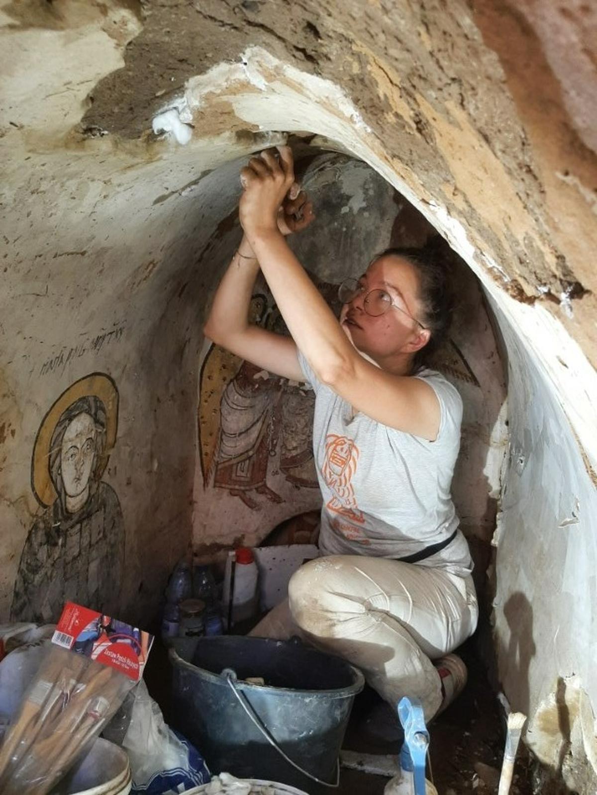 An archaeologists works to preserve the paintings in the underground chamber.