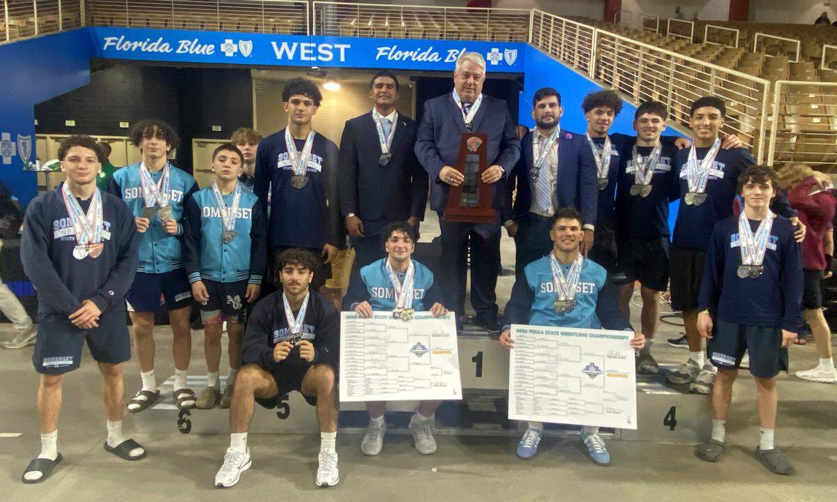 Somerset Academy wrestlers and coaches gather on the medal stand with the FHSAA Class 2A boys wrestling state runners-up trophy on Saturday at Silver Spurs Arena in Kissimmee.