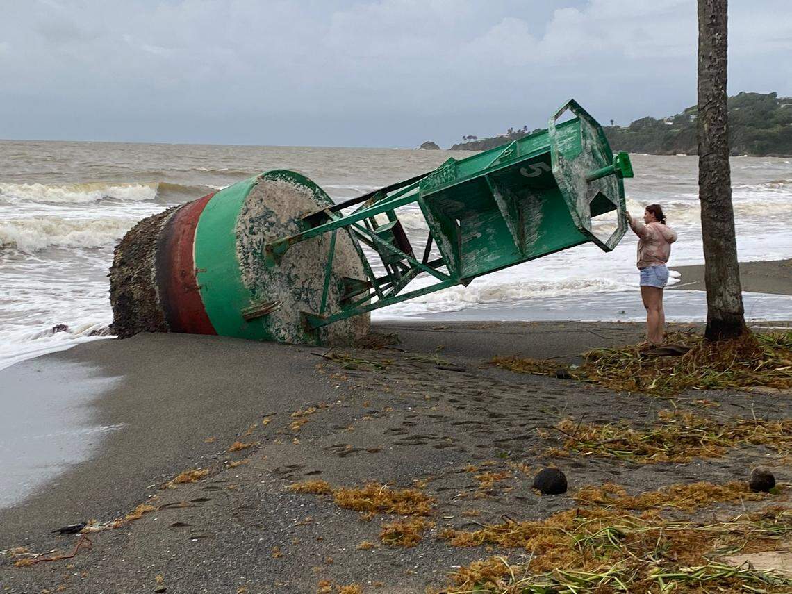 A woman stands next to a buoy pulled ashore by waves at a port in the eastern town of Yabucoa on Monday, Sept. 19, 2022. Hurricane Fiona made landfall in Puerto Rico on Sunday, Sept. 18.