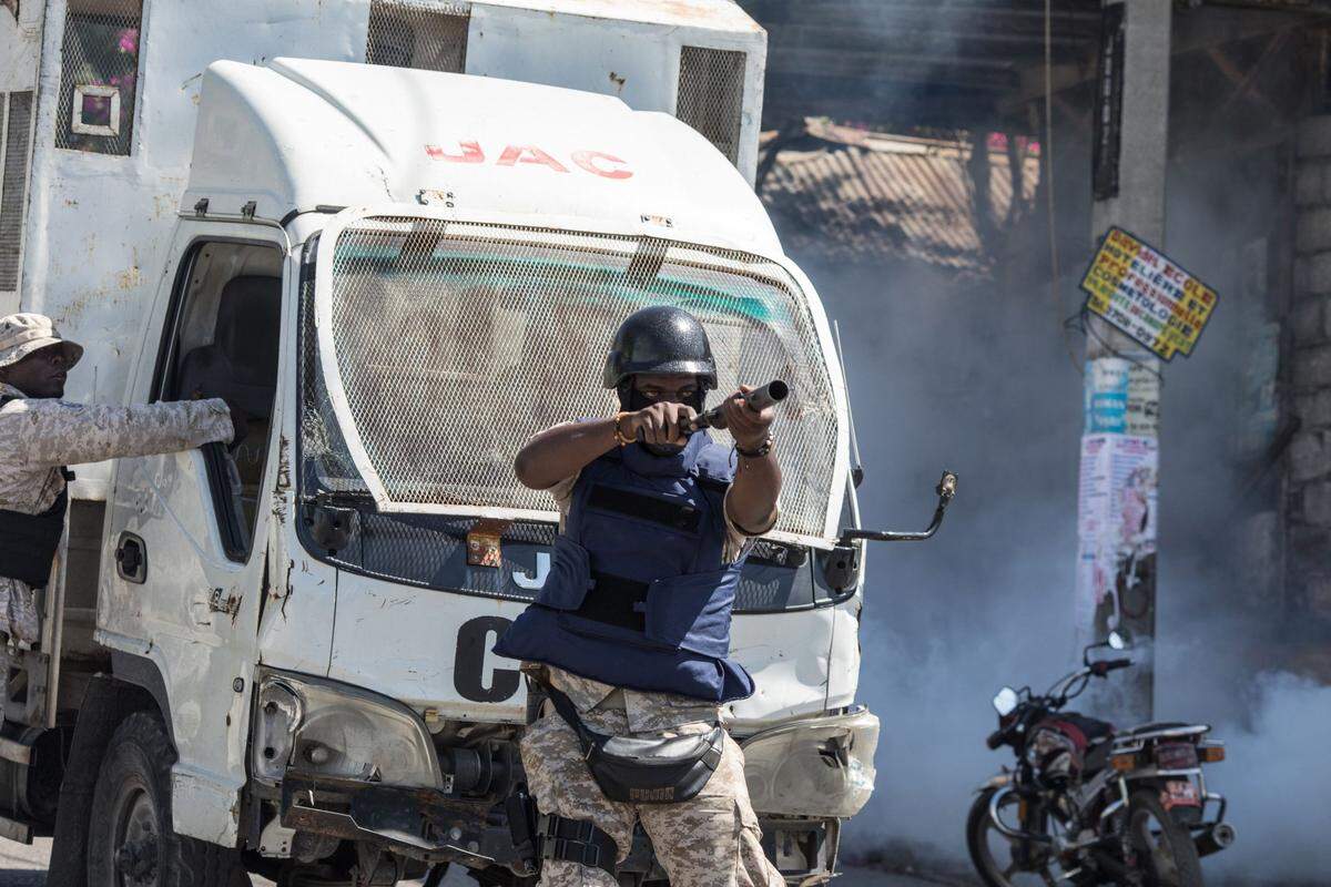 A police officer shoots tear gas toward a group of journalists gathered to cover a protest against the Haitian president, in Port-au-Prince, February 10, 2021. Haitian police fired tear gas on hundreds of protesters who were marching against President Jovenel Moïse in Port-au-Prince on February 10, and attacked journalists covering the demonstration, in the latest clashes to mark the country’s political crisis.