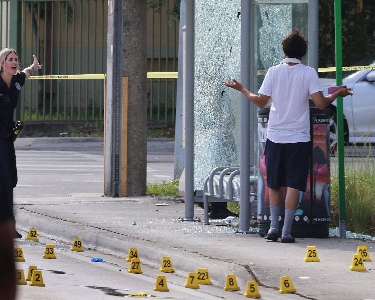 A Miami police officer gives a stern warning after a pedestrian walk into the active crime scene where four people were shot, two of them killed, after an early morning shooting in Miami on Monday, June 16, 2025.