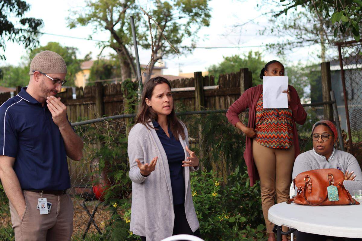 As members of FIU’s Neighborhood Health Education Learning Program present to the group, one woman from Empowering Resilient Women translates in creole for other cohort members.