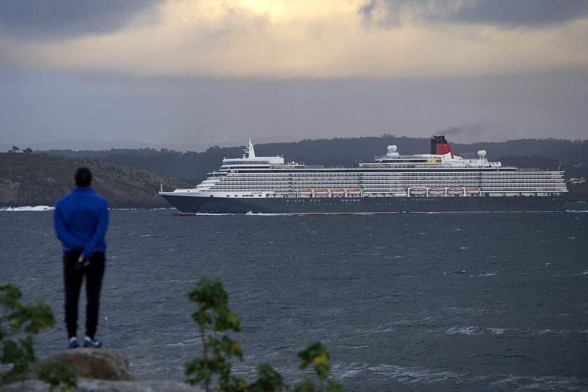 A person looks at the cruise ship Queen Elizabeth, leaving off the coast Spain in 2022.