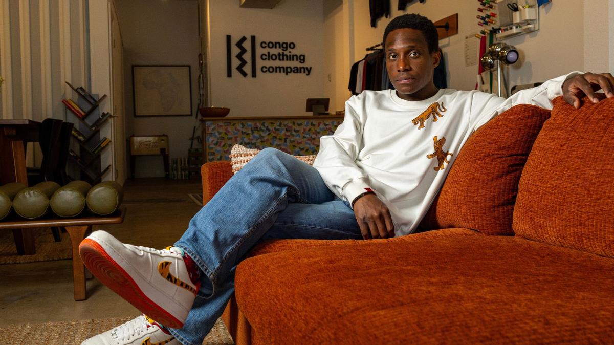 El propietario y operador de Congo Clothing Company, Milain Fayulu, sentado en la tienda el viernes 21 de junio de 2024, en Miami, Florida.